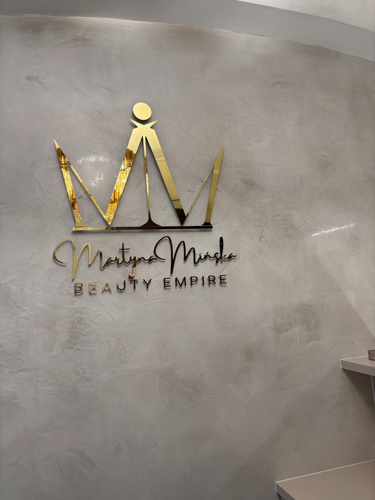 Złoty znak Martyna Mińska Beauty Empire na ścianie salonu